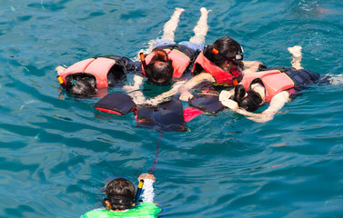 Group of friends snorkeling in sea with trainer
