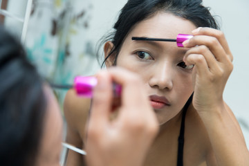 Portrait of woman as applying makeup in a mirror