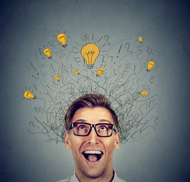 Happy man in glasses looking up with light idea bulb above head