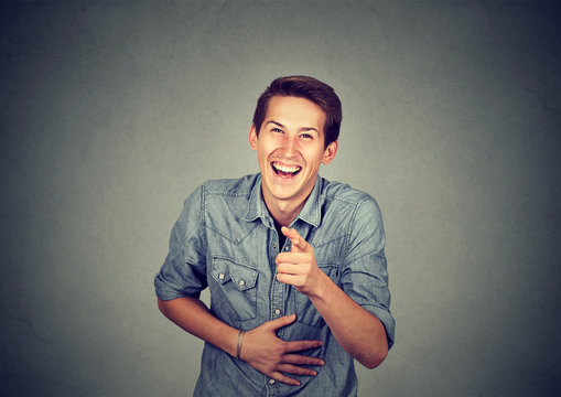 Portrait laughing young man pointing with finger