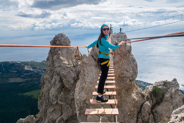 The girl goes on suspension bridge over the precipice