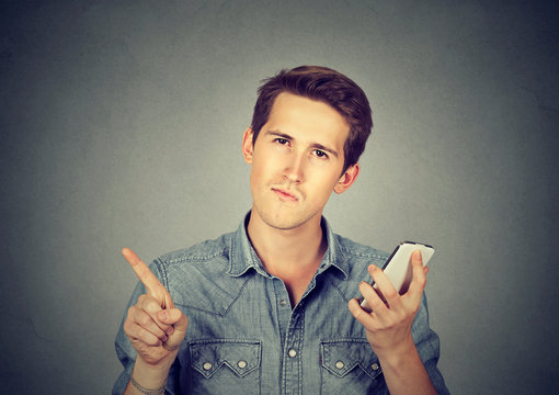 man with cell phone showing no, don't, attention with finger gesture