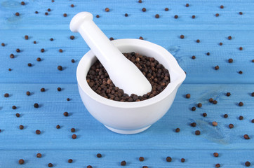 Black pepper in white mortar on blue boards