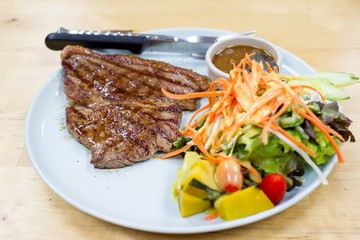 Medium well beef steak with salad close up.