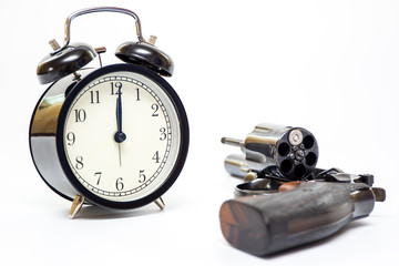 Classic alarm clock and .38 revolver handgun close up on white background.