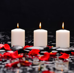 Many rose petals with three candle and therapy stones 