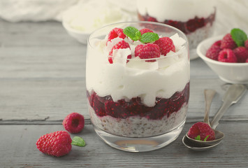 Healthy breakfast, desert, with chia seed pudding, cream, raspberry jam, coconut flakes and fresh berries