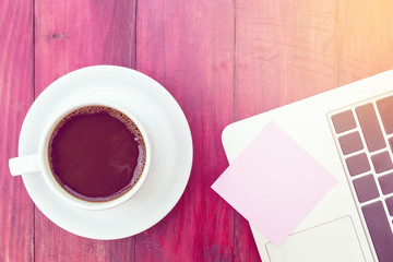 Empty pink pos it and laptop keyboard, on red wood background
