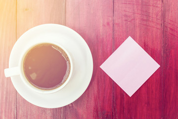 Empty pink pos it and coffee cup on red wood background