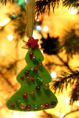 Handmade Christmas gifts in mess with toys, candles, fir, ribbon,beads, wooden vintage on  fir tree branches and gold lights bokeh background.