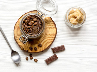 jar with coffee-chocolate body scrub top view wooden background