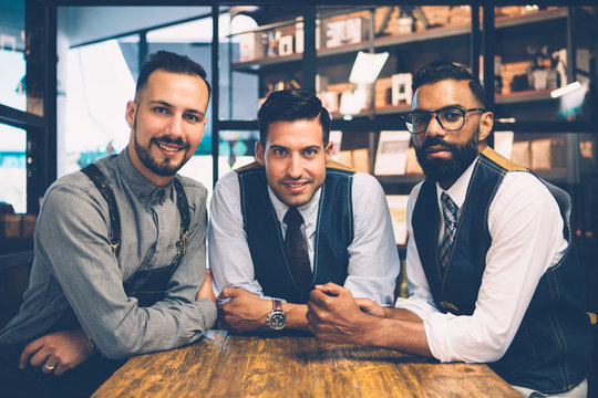 Smiling men at wooden table looking at camera