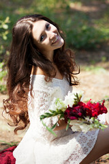 Nice girl sits with a bouquet in hands and laughs
