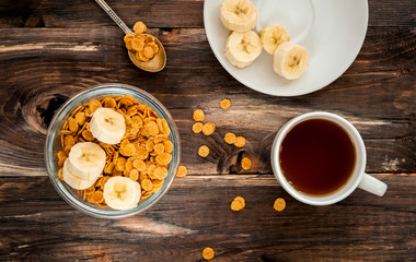 flakes in bowl, tea cup on wooden background top view