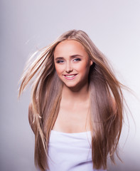 Fototapeta premium Beautiful young girl with long hair on a light background in the studio
