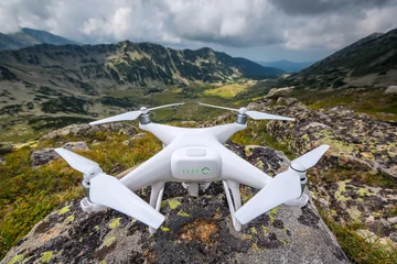 Fotobehang Flying drone quadcopter above the mountain hills © ValentinValkov
