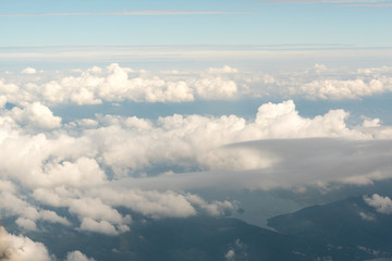 Fototapeta na wymiar Cloudscape view with mountain above white clouds and blue sky from airplane