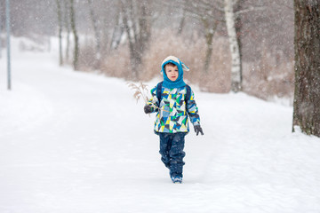 Cute little boy with backpack, going on a ski holiday, walking i