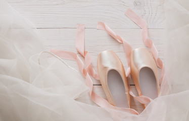 Pink ballet pointe shoes and tutu on white wood background © Prostock-studio