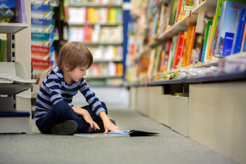 Adorable little child, boy, sitting in a book store