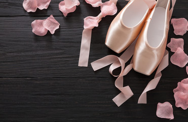Pink ballet pointe shoes on black wood background