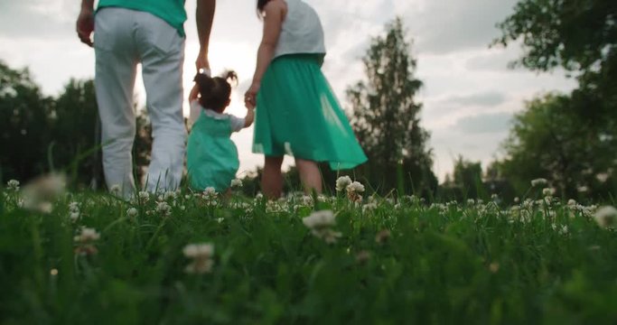 young Asian family with one year old baby walks in the Park holding hands, slow motionv