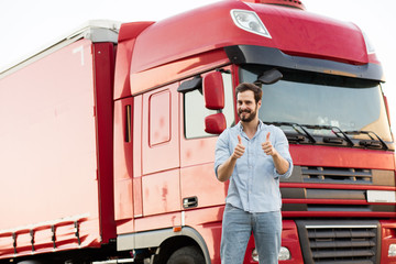 masculine truck driver in jeans with his truck behind