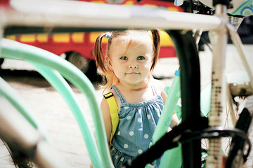 Beautiful little girl with two tails standing by bicycle