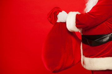 Santa Claus hand holding red sack full of presents over