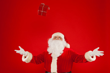 Fototapeta na wymiar Photo of Santa Claus gloved hand with giftbox, on a red background. Christmas