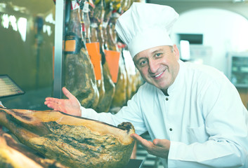 Positive mature man working with iberian jamon