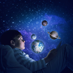 Boy with tablet in his bed