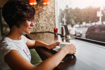 Woman in vintage cafe sitting and drinking coffee by the window looking the charming city street. The concept of urban life