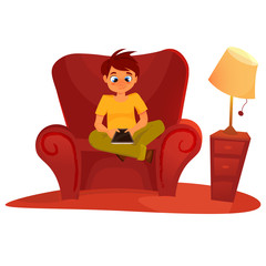 boy sitting on the armchair and playing tablet