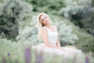 Fototapeta na wymiar beautiful, gentle and young woman sits on green grass