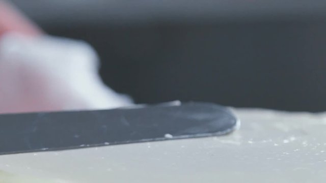 Close-up: biscuit cream in the form of a spiral on the cake. Confectionery spatula dub cream. Cooking cake with cream. Cake with cream. Preparation of cake in a candy store.