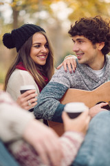 Friends having picnic outdoor. Man playing guitar.