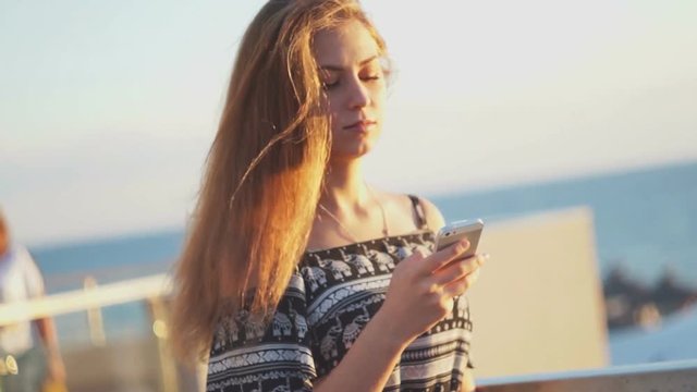 Young girl on the beach with your smartphone. Sunset