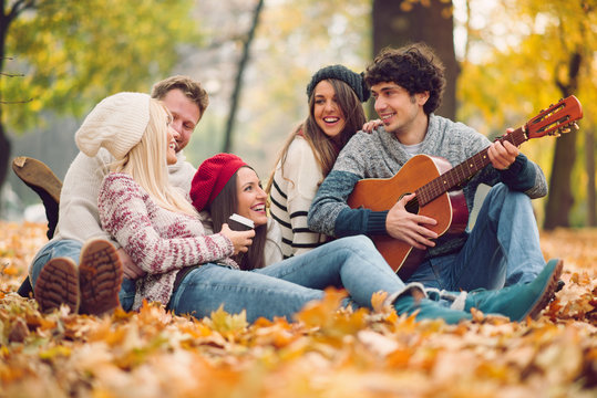 Friends having picnic outdoor. Man playing guitar.