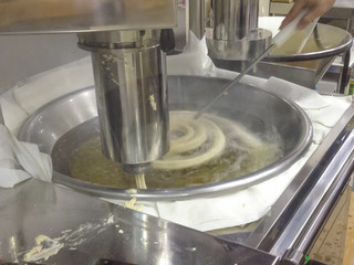 Churros elaboration process. Churros maker fry pastry dought in spiral shape