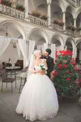 Lovely happy wedding couple, bride with long white dress posing in beautiful city