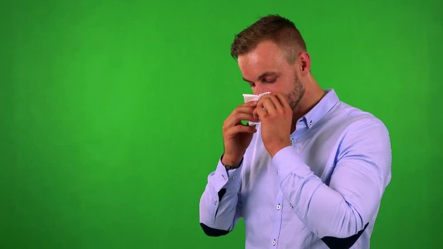 young handsome business man blow one's nose - green screen - studio