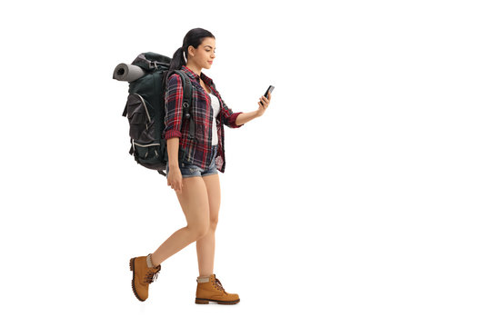 Female Hiker Walking And Looking At Cell Phone