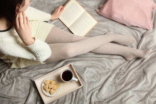 Young girl reading a book on the bed. Top view