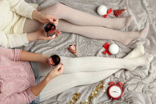 Women with hot mulled wine in hands on the bed. Top view point. Soft cozy photo. 