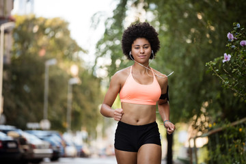 Runner woman with earphones and armband tied to her left hand.
