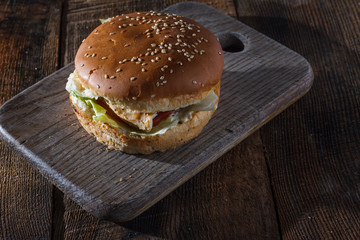 Tasty grilled burger with lettuce and mayonnaise ,on a rustic wo