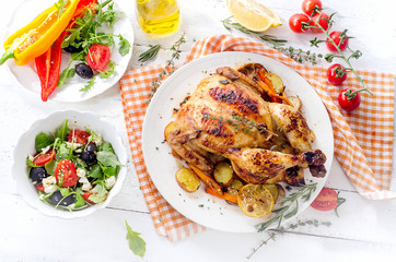 Roasted chicken with vegetables and salad on a wooden background