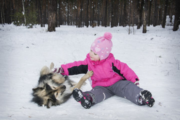 Winter in the forest little girl playing with a dog.