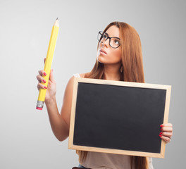 portrait of a beautiful young woman holding a board and a big pencil
